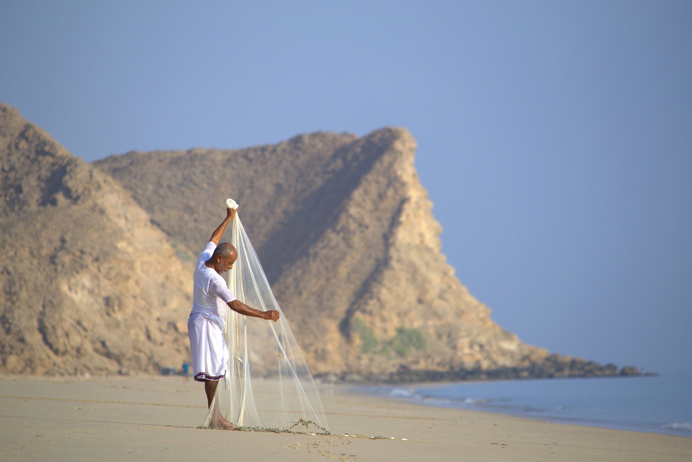 Fisherman casting a net on As Sifah beach in Oman